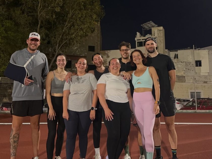 Members at an evening Hyrox track run session on an outdoor running track