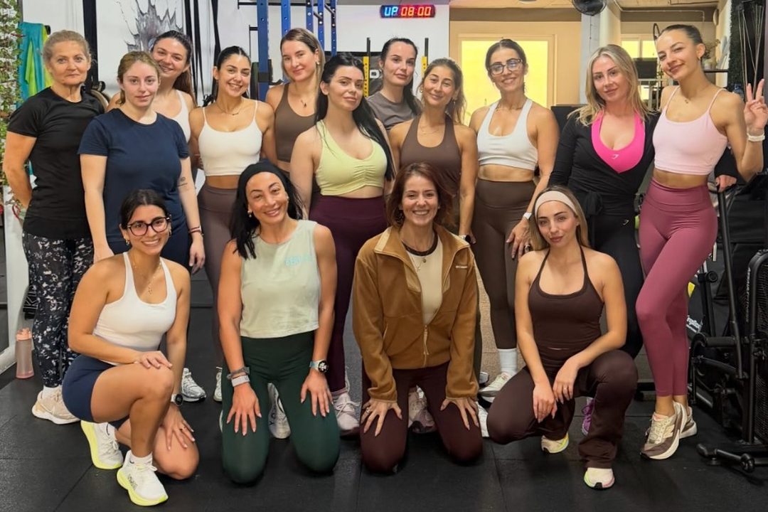 Fourteen women in gym kit posing together on the Beat It studio floor